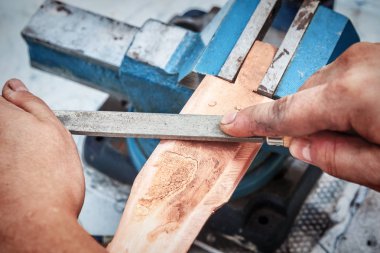 Bakır kütük bir dosyayla taşlama