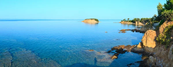 早晨爱琴海海岩石海岸看法以摄影师的阴影在清楚的水表面 Nikiti Sithonia 哈尔基迪基 两个镜头缝合全景 — 图库照片