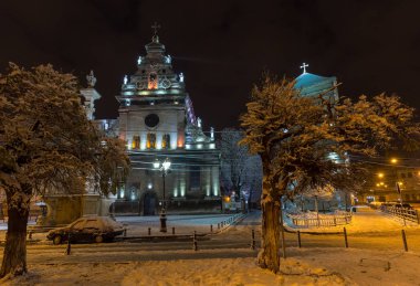 Gece kış Lviv (Ukrayna) şehir cityscape aydınlatılmış. Bernardine Kilisesi ve Manastırı (Kilise St. Andrew) üst, yerleşik in17th yüzyıl. Ve anıt Dukla Saint John için devam et, 1736 inşa.