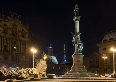LVIV, UKRAINE - DECEMBER 10, 2017: Beautiful night winter cityscape in the center of Lviv city, Ukraine. Monument to Adam Mickiewicz (built in 1904). clipart