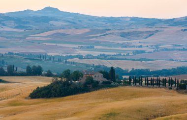 Tuscany, İtalya-23 Haziran 2017: House, tepeler, buğday alanı ile yaz sabah gündoğumu kırsal İtalya güzel manzara.