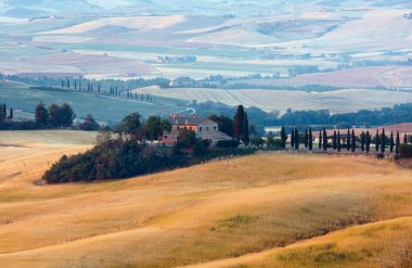 Tuscany, İtalya-23 Haziran 2017: House, tepeler, buğday alanı ile yaz sabah gündoğumu kırsal İtalya güzel manzara.
