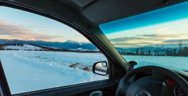 Evening twilight winter Chornohora mountain ridge scenery view thru car windshield (Ukraine, Carpathian Mountains, Hoverla, Petros and other alps from Yablunytsia pass). Car model unrecognizable. clipart