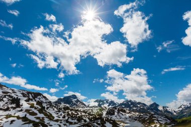 Güneşli alp dağ manzarası ile güneş ve mavi gökyüzü (Warth,: Vorarlberg, Austria) bulutlarda Hochtannbergpass bahar. Bazı güneş patlaması etkisi.