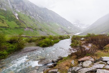 Passo del San Gottardo ya da St. Gotthard Pass yaz puslu, yatay su akışı (İsviçre). Yağmurlu hava.