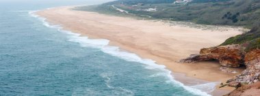 Sandy okyanus plaj Nazare şehir (Portekiz). Bahar puslu günü. Panorama.