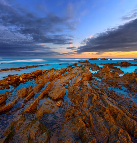 Twilight ocean coast with ribbed stratiform rock