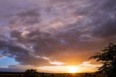 Yağmurdan sonra bahar çayırı, gün batımından önce bulutlu bir akşam gökkuşağı, kırsal tepeler ve uzak görüşte tarlalar. Doğal mevsim, hava, iklim, kırsal güzellik konsepti.