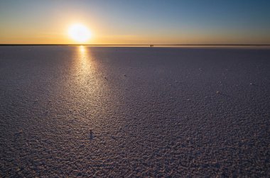 Genichesk pembe üzerinde gün batımı son derece tuzlu göl (kristal tuz kalıntılarıyla mikro algler tarafından renklendirilmiş), Ukrayna. İnsanlar tanınmaz halde..