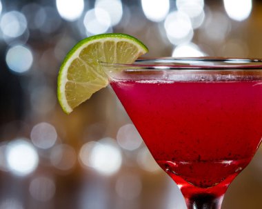 bir ahşap bar ayarı içinde limon dilimi ile süslenmiş bardağın dibinde yüzen küçük huckleberry tohumları ile kırmızı soğutulmuş martini