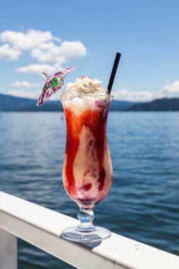 Pina colada yenileme karışık çilek ile garnitür olarak görev yaptı ve doğal mavi su arka plan olarak bir seyahat tatil kavramı ile krem şanti ile tepesinde