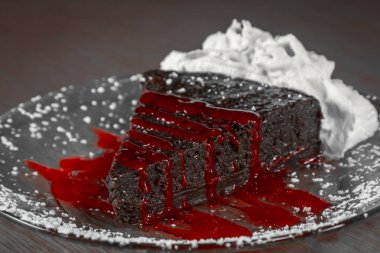 slice of a rich and dense flourless chocolate cake served with a raspberry sauce clipart