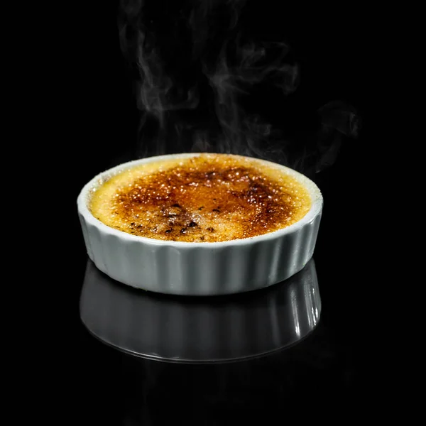 close up of a cremebrule with smoke from the burned sugar isolate don a black background