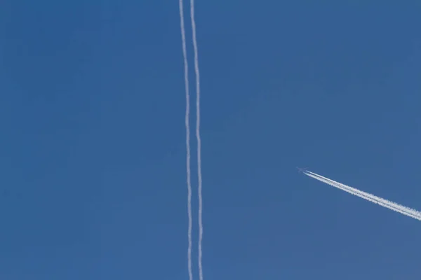 飛行機は美しい青い空を覆う大気中に何かの厚い噴煙を春します — ストック写真