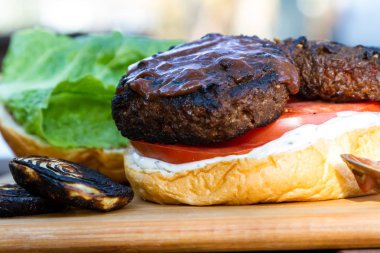 bir ev yapımı sos ve taze domates ve marul bir ahşap kesme tahtası üzerinde ızgara bitki esaslı burger hizmet