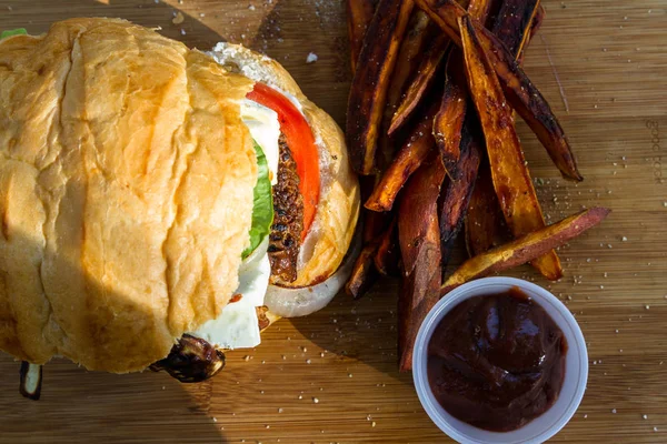 烤植物汉堡配上自制的酱汁红薯薯条在木制切菜板上 — 图库照片