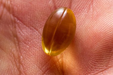 close up of a CBD oil capsule made from hemp on a persons hand clipart