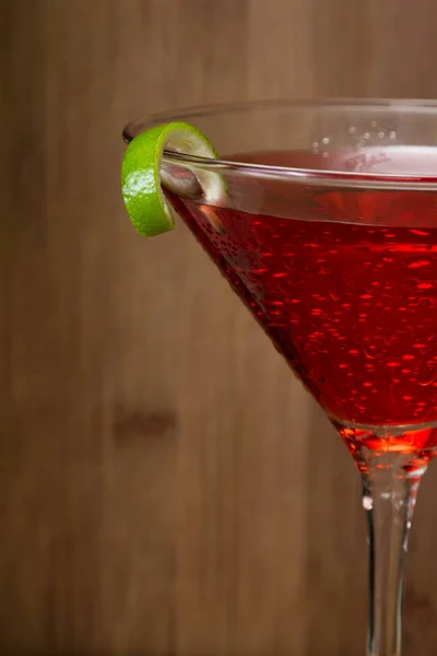Zamknąć Cosmo Serwowane Kieliszku Martini Przyozdobionym Limonki Nad Podłoże Drewniane — Zdjęcie stockowe