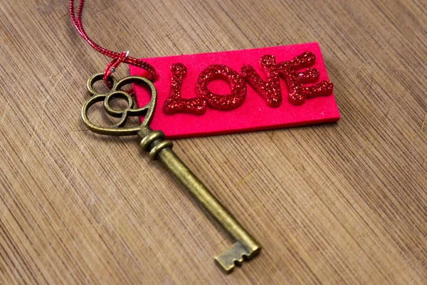 キラキラ文字の木製の背景に愛という言葉をスペルで赤タグで古いキーを使用して概念のイメージ — ストック写真