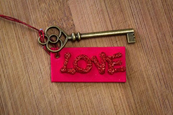 キラキラ文字の木製の背景に愛という言葉をスペルで赤タグで古いキーを使用して概念のイメージ — ストック写真
