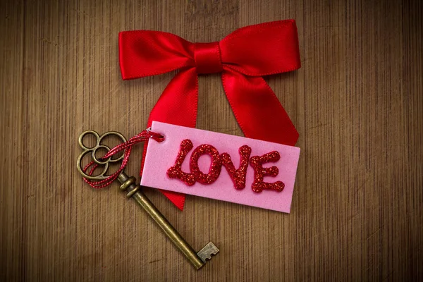 愛という言葉をスペル チェック赤キラキラ文字でピンクのタグが古いキーを使用して概念図 — ストック写真