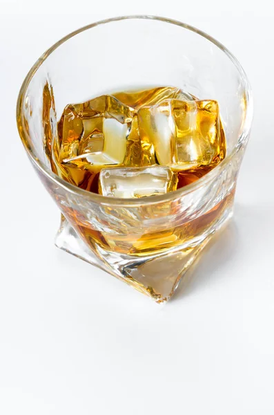 Close up of a tumbler glass with straight Kentucky bourbon served on the rocks isolated on a white background