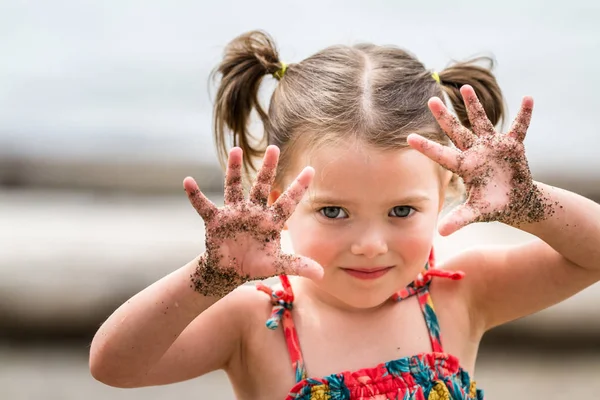 Menina com areia em suas mãos — Fotografia de Stock