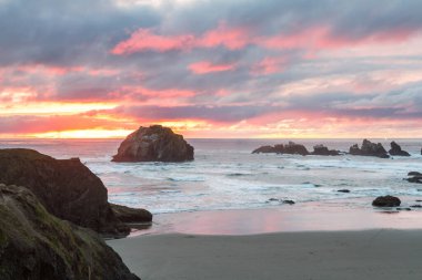 Günün sonunda plajda koyu bulutlarda biraz renk ve belirgin kaya karakteristik Face Rock State Park, Bandon Oregon