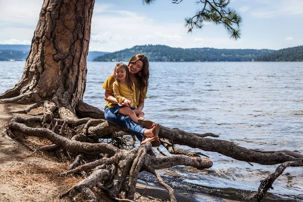 Mother Daughter Matching Outfits Sitting Exposed Roots Tree Lake Coeur — Stock Photo, Image