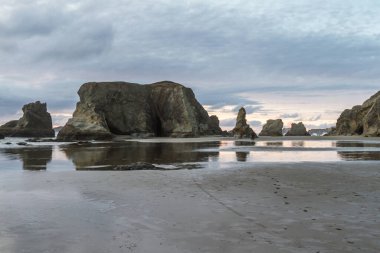Günün sonunda plajda koyu bulutlarda biraz renk ve belirgin kaya karakteristik Face Rock State Park, Bandon Oregon
