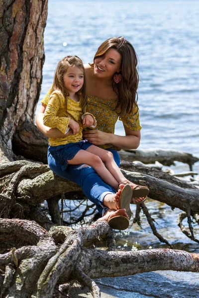 Mother Daughter Matching Outfits Sitting Exposed Roots Tree Lake Coeur — Stock Photo, Image