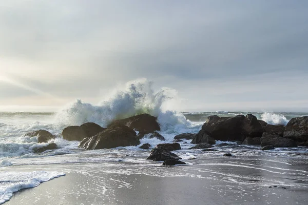 オレゴン州ネシカビーチのロッキー海岸線午後遅く 太陽が地平線に接近し 波が岩に衝突する — ストック写真