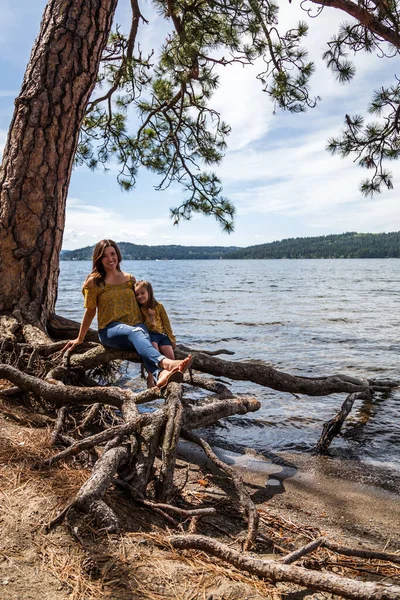 Mother Daughter Matching Outfits Sitting Exposed Roots Tree Lake Coeur — Stock Photo, Image