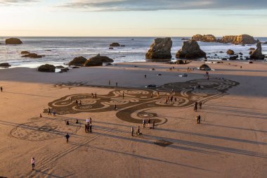 Bandon by the Sea, Oregon / USA - 08 Mart 2020: İnsanlar gün batımında Face Rock State Park plajında yürüyorlar Kum Çemberi ekibi tarafından oluşturulan bir labirentte