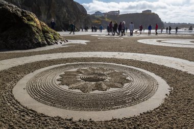 Bandon by the Sea, Oregon / USA - 13 Mart 2020: İnsanlar Kum Çemberi ekibi tarafından oluşturulan plajda labirentte inanılmaz detaylı sanat eserleriyle yürüyorlar