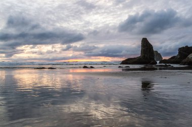 Günün sonunda plajda koyu bulutlarda biraz renk ve belirgin kaya karakteristik Face Rock State Park, Bandon Oregon