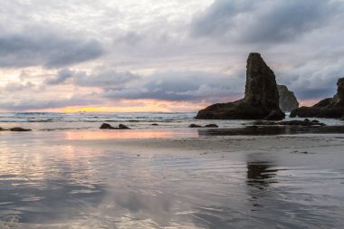 Günün sonunda plajda koyu bulutlarda biraz renk ve belirgin kaya karakteristik Face Rock State Park, Bandon Oregon