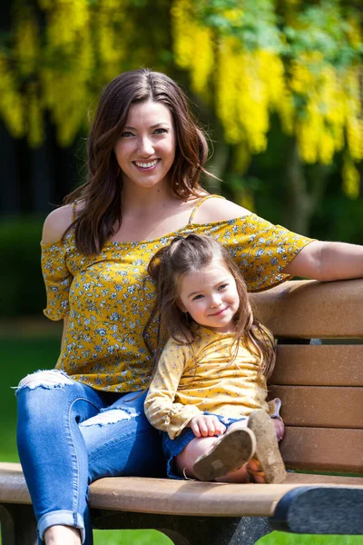 Mãe Filha Com Roupas Combinando Sentado Banco Com Flores Amarelas — Fotografia de Stock