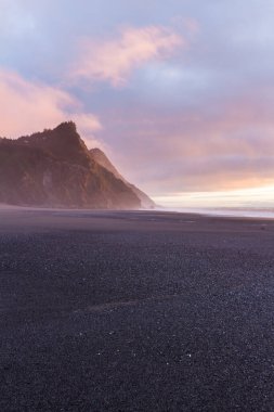 Batan güneşin muhteşem yumuşak ve renkli ışığı. Günün sonunda sahnenin sonuna dram ve güzellik katıyor. Güney Oregon sahilinde Cape Sebastian 'la.