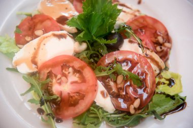 Mozzarella peyniri, çam fıstığı ve zeytin ile taze domates.