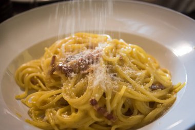 Carbonare pasta pastırma ile sıcak ve yumurta sosu ile parmesan peyniri serpilir.