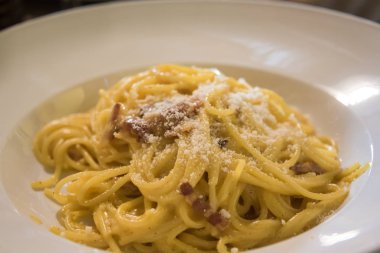 Beyaz tabakta makarna Carbonara parmesan ile .