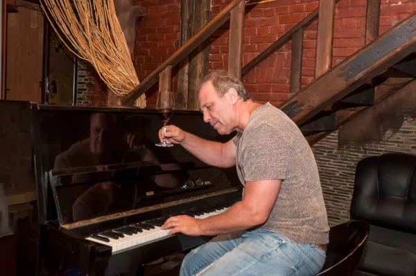 Man playing piano and drinking wine . — Stock Photo, Image