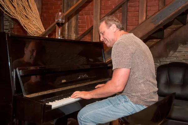 Homem tocando piano e bebendo vinho  . Fotos De Bancos De Imagens