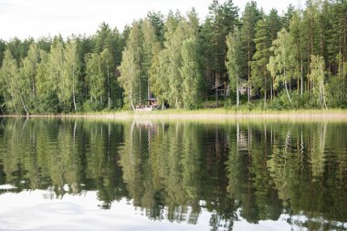 Gün batımında göl kıyısının panoraması suda yansıması ile. Finlandiya .