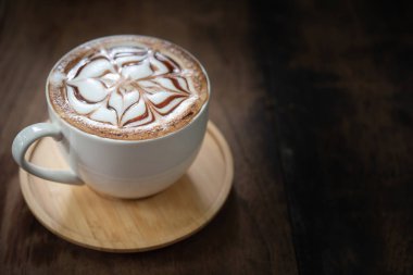 Bir fincan kahve güzel latte sanat siyah rustik zemin üzerine. Ahşap bir masa üzerinde kahve