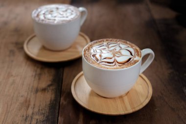 İki bardak kahve güzel latte sanat siyah rustik zemin üzerine. Ahşap bir masa üzerinde kahve