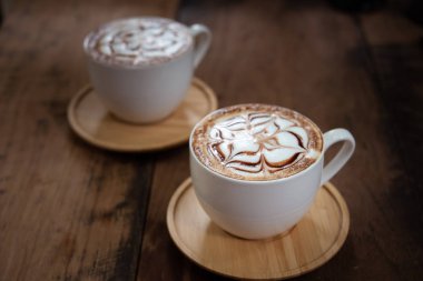 İki bardak kahve güzel latte sanat siyah rustik zemin üzerine. Ahşap bir masa üzerinde kahve