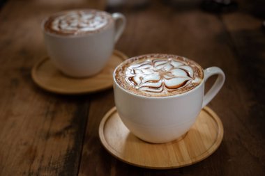 İki bardak kahve güzel latte sanat siyah rustik zemin üzerine. Ahşap bir masa üzerinde kahve