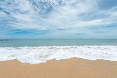 Yumuşak dalgalar üzerinde kum plaj. Beyaz kabarcıklar sahilde okyanus dalgaları seashore tarafından yaratılmıştır. Akış dalga ile tropikal plaj.
